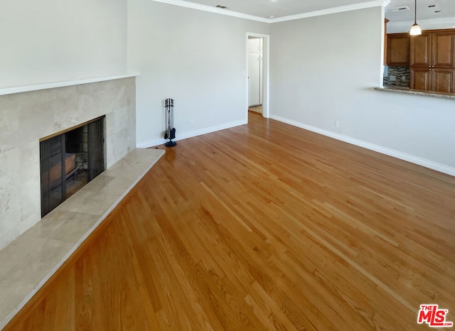 unfurnished living room with a fireplace, hardwood / wood-style floors, and crown molding