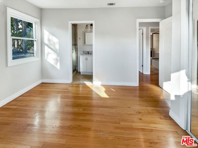 unfurnished bedroom with light wood-type flooring and ensuite bathroom