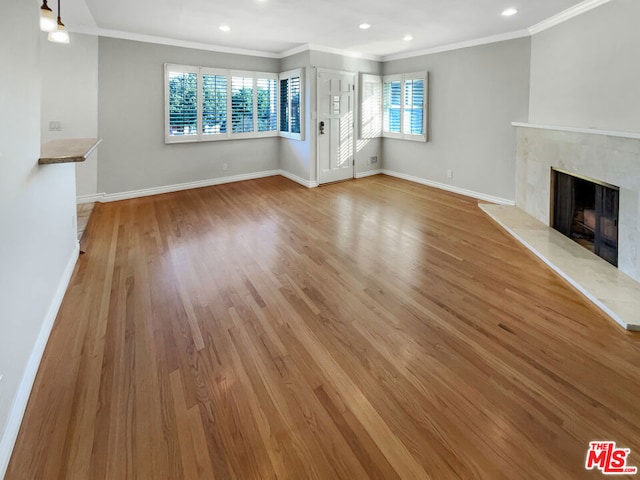 unfurnished living room featuring light hardwood / wood-style floors, crown molding, and a high end fireplace