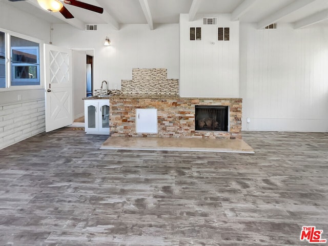 unfurnished living room with beam ceiling, ceiling fan, a fireplace, and wood-type flooring