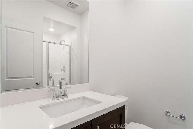 bathroom featuring vanity, toilet, and a shower with door