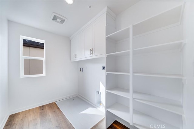 laundry area featuring hookup for an electric dryer, cabinets, hardwood / wood-style floors, and washer hookup