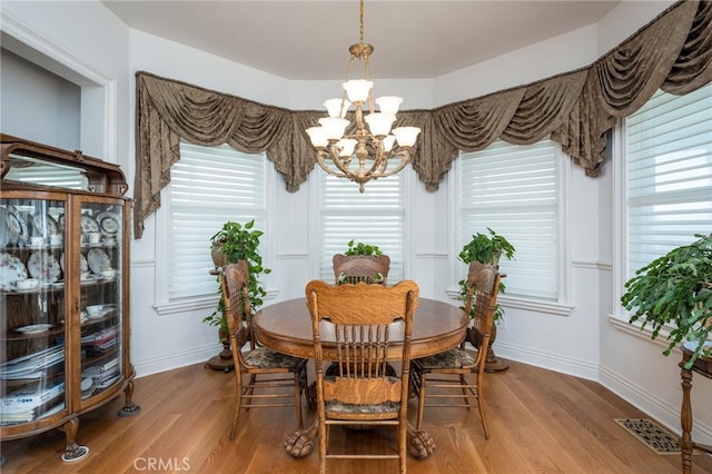 dining space featuring light hardwood / wood-style flooring and a notable chandelier