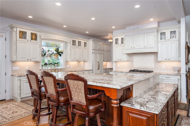 kitchen with a kitchen breakfast bar, paneled refrigerator, white cabinets, and a spacious island