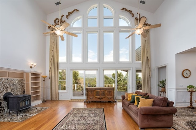 living room with light hardwood / wood-style flooring, plenty of natural light, a wood stove, and a high ceiling