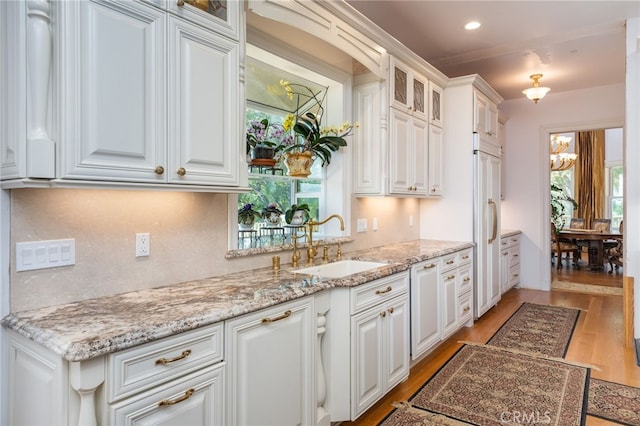 kitchen with a notable chandelier, light hardwood / wood-style flooring, white cabinets, and sink