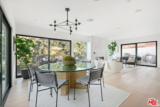 dining room featuring a notable chandelier, a wealth of natural light, and light wood-type flooring