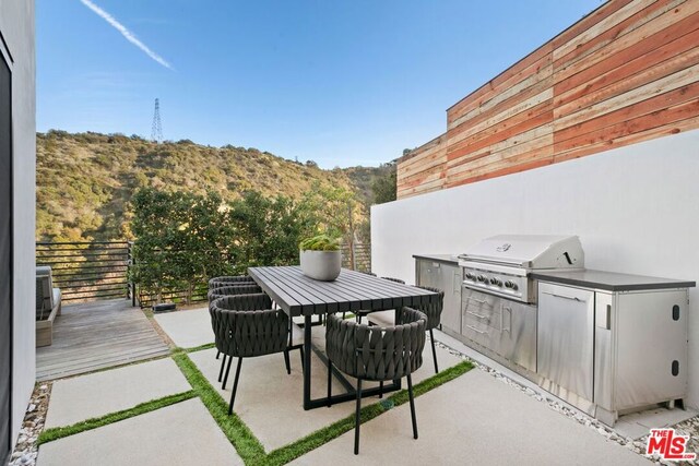 view of patio / terrace with an outdoor kitchen, a mountain view, and grilling area