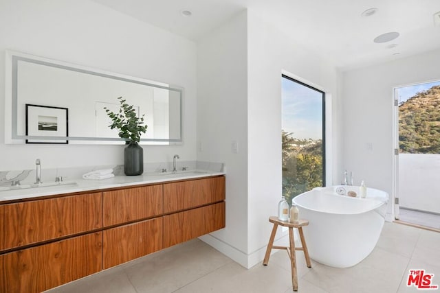 bathroom featuring vanity, a tub, and tile patterned flooring