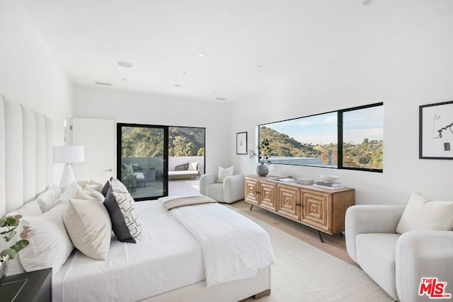 bedroom featuring access to outside, multiple windows, and light wood-type flooring