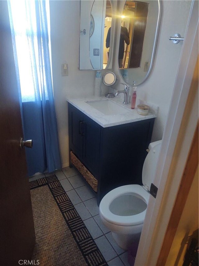 bathroom with toilet, vanity, and tile patterned flooring