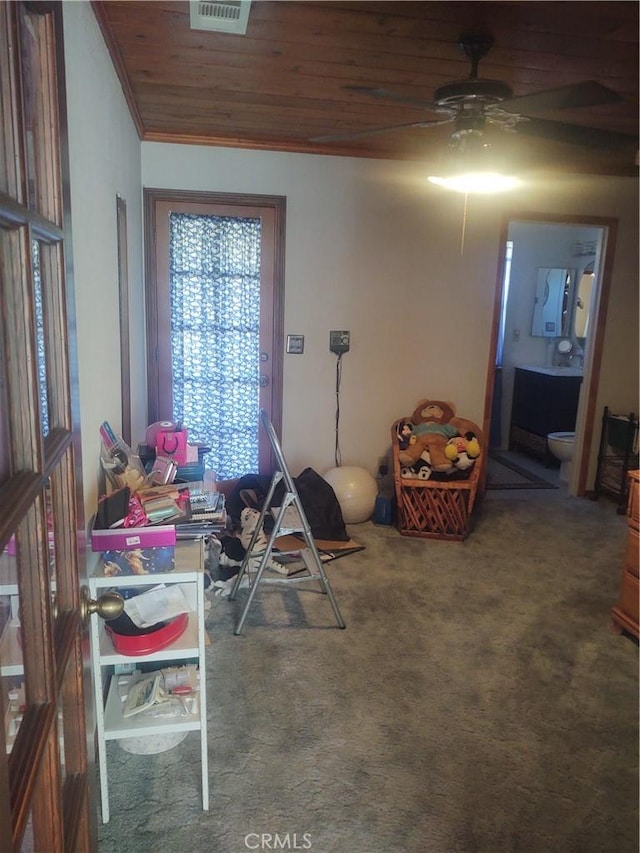 interior space featuring ceiling fan, carpet flooring, crown molding, and wooden ceiling