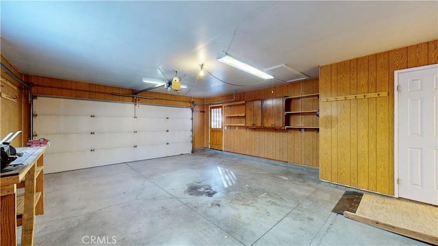 garage featuring a garage door opener and wooden walls