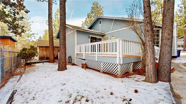 snow covered rear of property featuring a deck