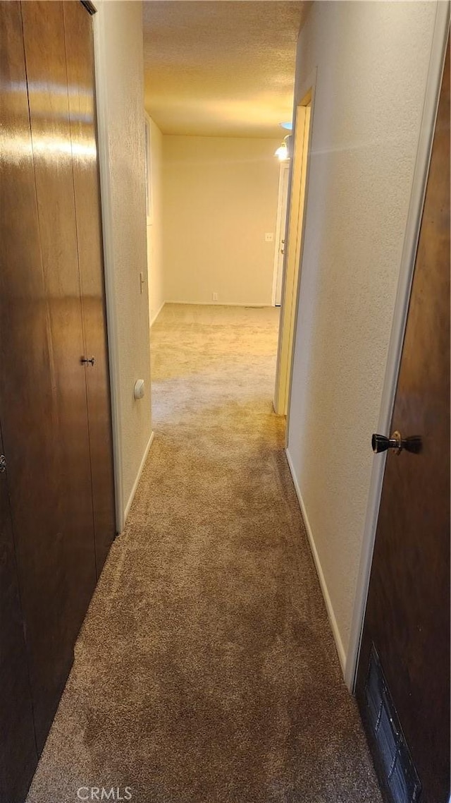 hall with light carpet and a textured ceiling