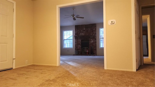 unfurnished living room featuring ceiling fan, a brick fireplace, and light carpet