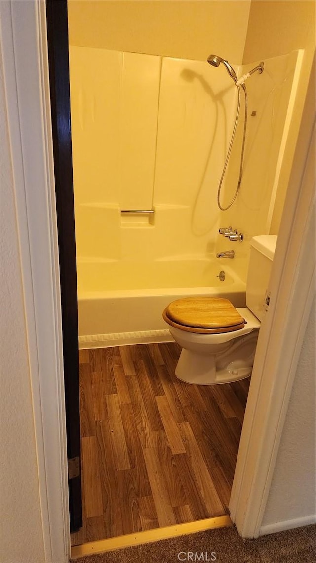 bathroom with hardwood / wood-style flooring, shower / bathtub combination, and toilet