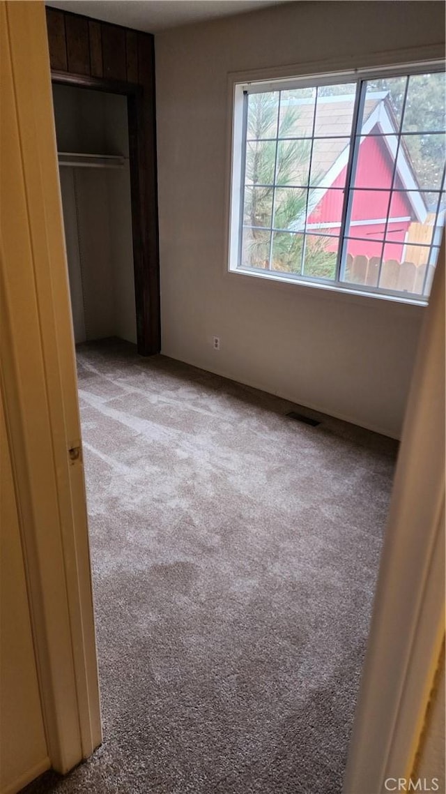 unfurnished bedroom with light carpet and a closet