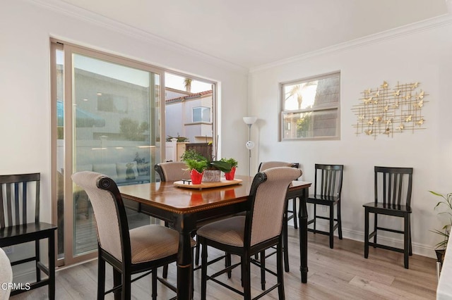 dining area with light hardwood / wood-style floors and crown molding