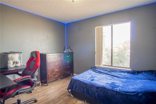 bedroom featuring multiple windows, a textured ceiling, and light wood-type flooring