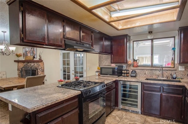 kitchen featuring a stone fireplace, sink, light tile patterned floors, black gas stove, and beverage cooler