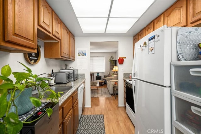 kitchen with white appliances, light hardwood / wood-style floors, and sink