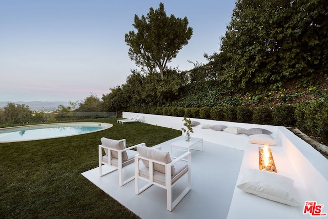 patio terrace at dusk featuring a yard and an outdoor fire pit