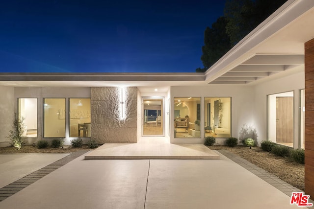 back house at twilight featuring a patio area