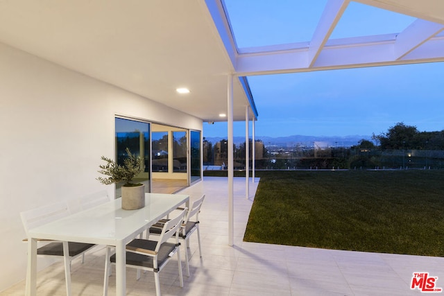 patio terrace at dusk featuring a yard and a mountain view