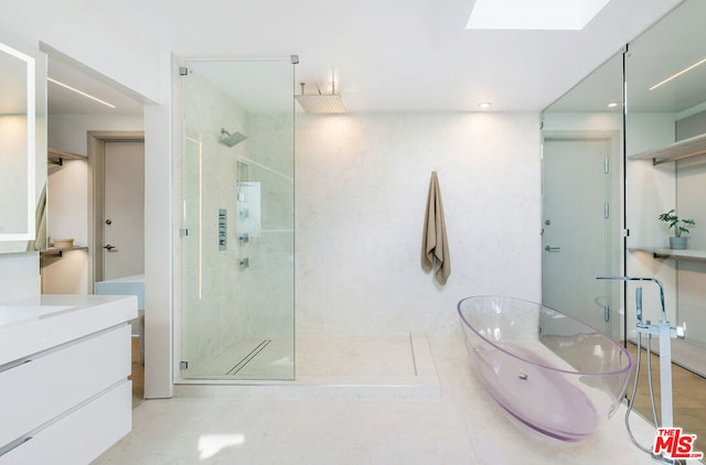 bathroom with vanity, a skylight, and separate shower and tub