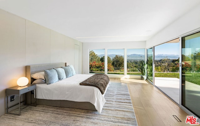 bedroom featuring a mountain view, access to outside, and hardwood / wood-style floors