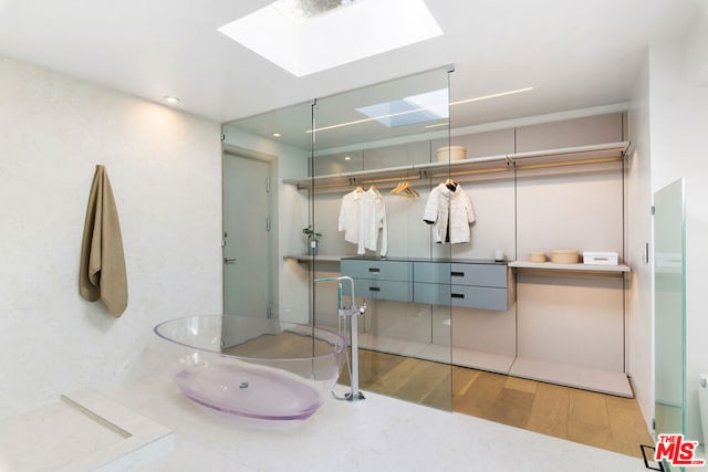 bathroom with vanity, hardwood / wood-style flooring, a shower, and a skylight