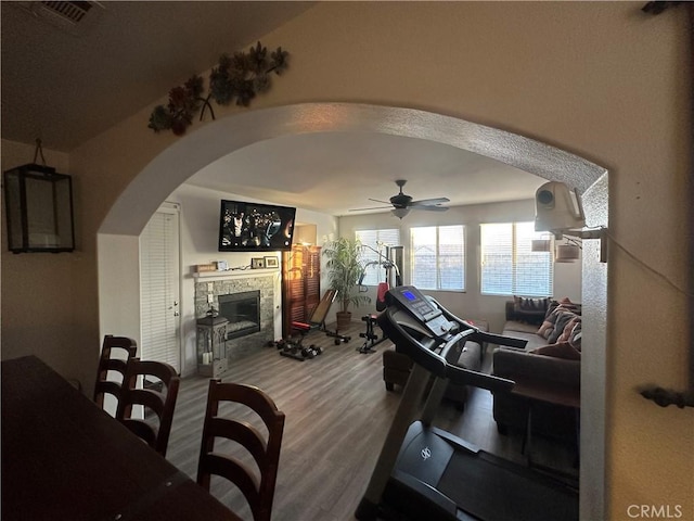 interior space featuring hardwood / wood-style floors, ceiling fan, and a stone fireplace