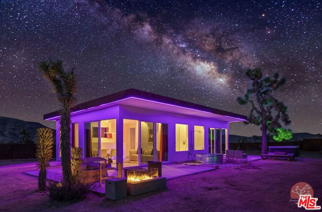 back house at night featuring a patio