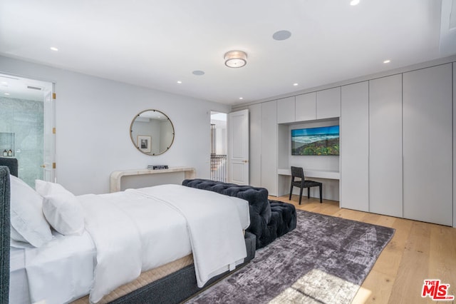 bedroom with built in desk and light wood-type flooring