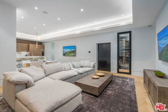 living room with beverage cooler, light hardwood / wood-style floors, and a raised ceiling