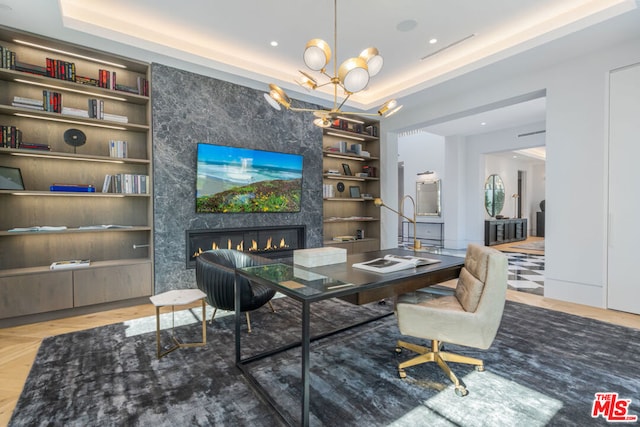 office space with a raised ceiling, a fireplace, and built in shelves