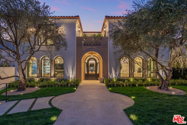 mediterranean / spanish-style home featuring a lawn and a balcony