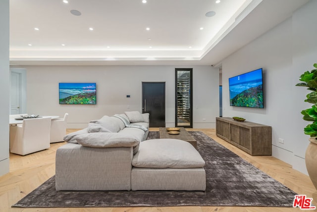 living room featuring light parquet floors and a tray ceiling