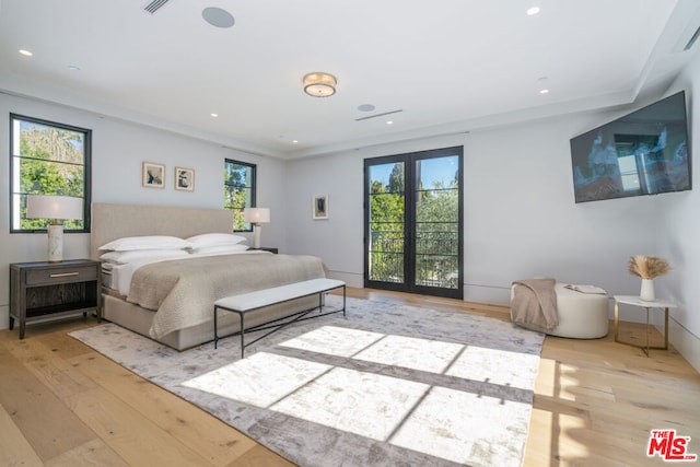 bedroom with french doors, light hardwood / wood-style flooring, and multiple windows