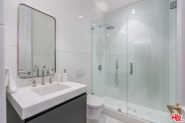 bathroom with tile walls, vanity, a shower with shower door, and toilet