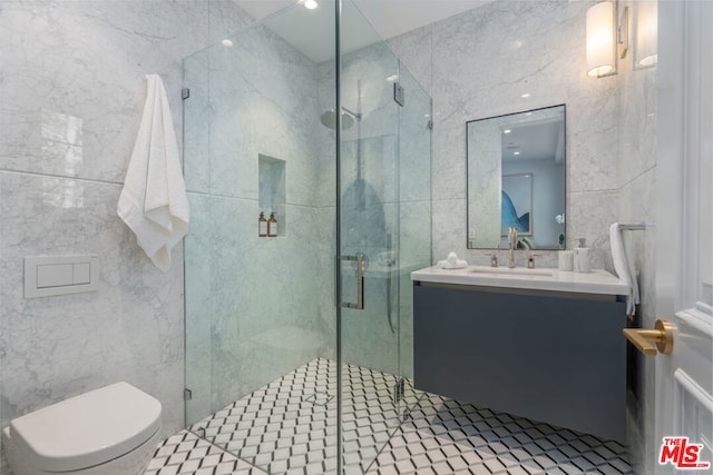 bathroom featuring vanity, a shower with shower door, toilet, and tile walls