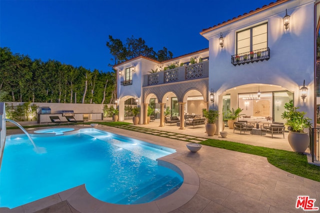 pool at twilight featuring an in ground hot tub, pool water feature, and a patio area