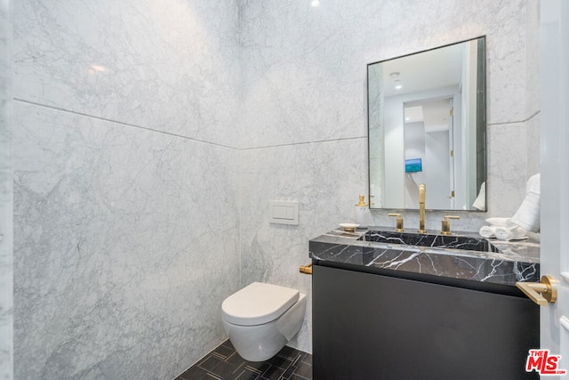 bathroom featuring toilet, vanity, tile patterned floors, and tile walls