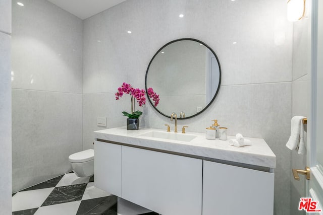 bathroom featuring tile walls, vanity, and toilet