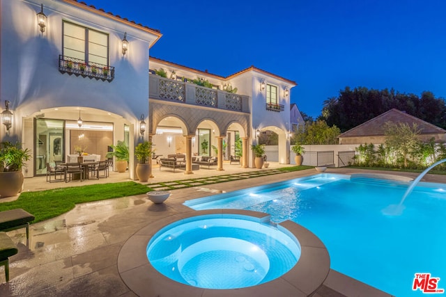 pool at night with an in ground hot tub, a patio area, and ceiling fan