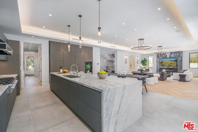 kitchen featuring a spacious island, sink, hanging light fixtures, and a tray ceiling