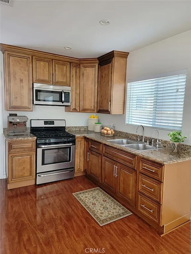 kitchen with appliances with stainless steel finishes, dark hardwood / wood-style floors, and sink