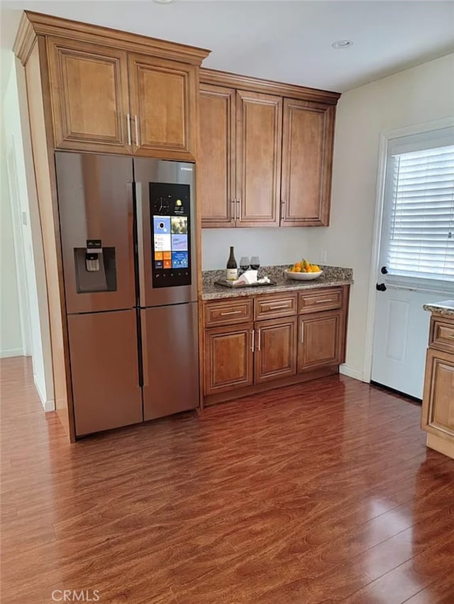 kitchen featuring stainless steel fridge, dark hardwood / wood-style flooring, and stone countertops