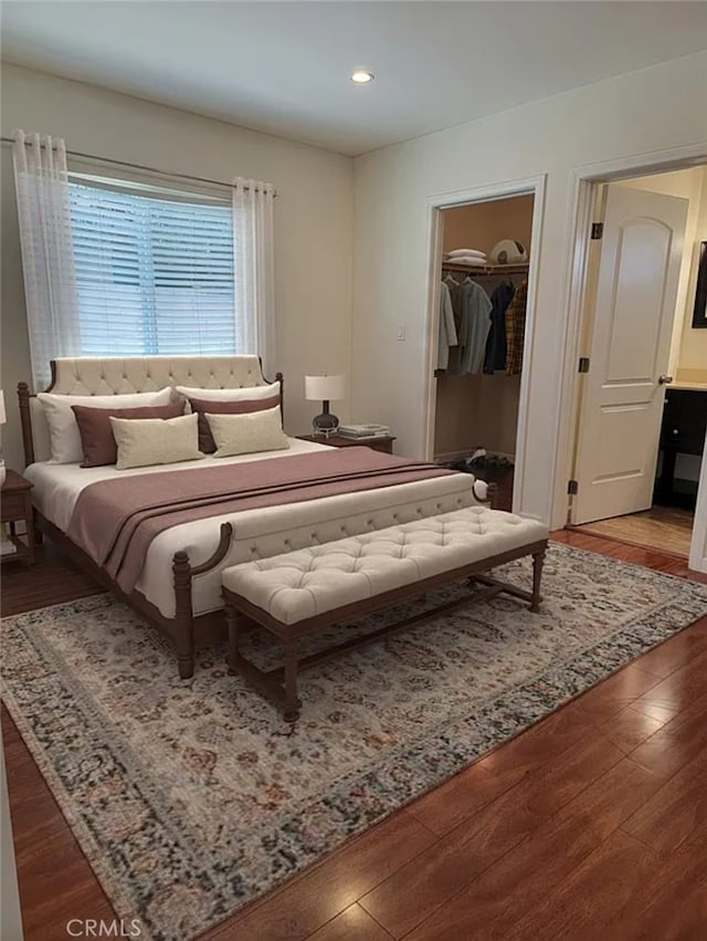 bedroom featuring a walk in closet, a closet, and hardwood / wood-style floors